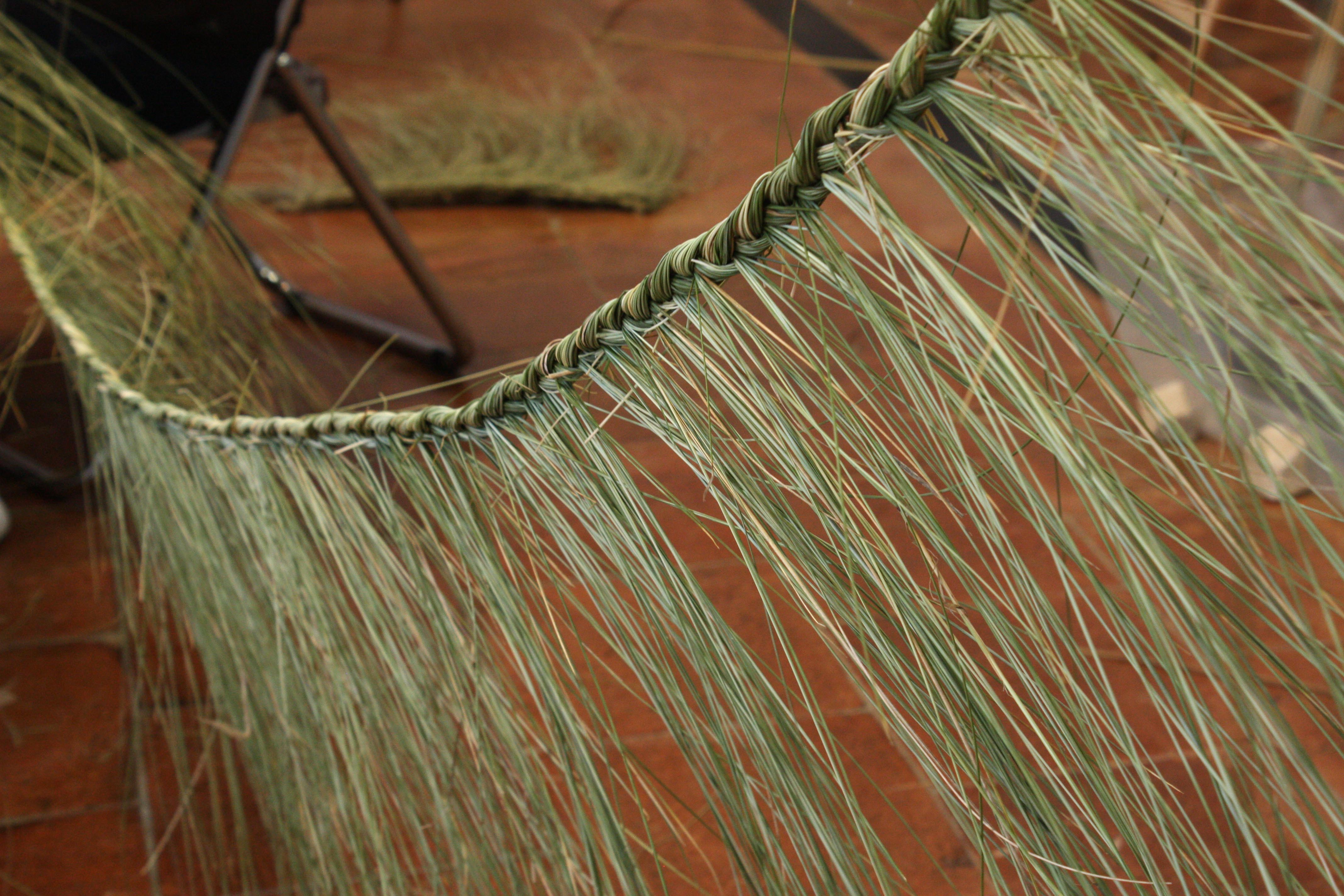 Fabrication des bordures du tapis : les fibres brutes sont délicatement insérées dans une longue tresse qui est ensuite cousue au bord du tapis